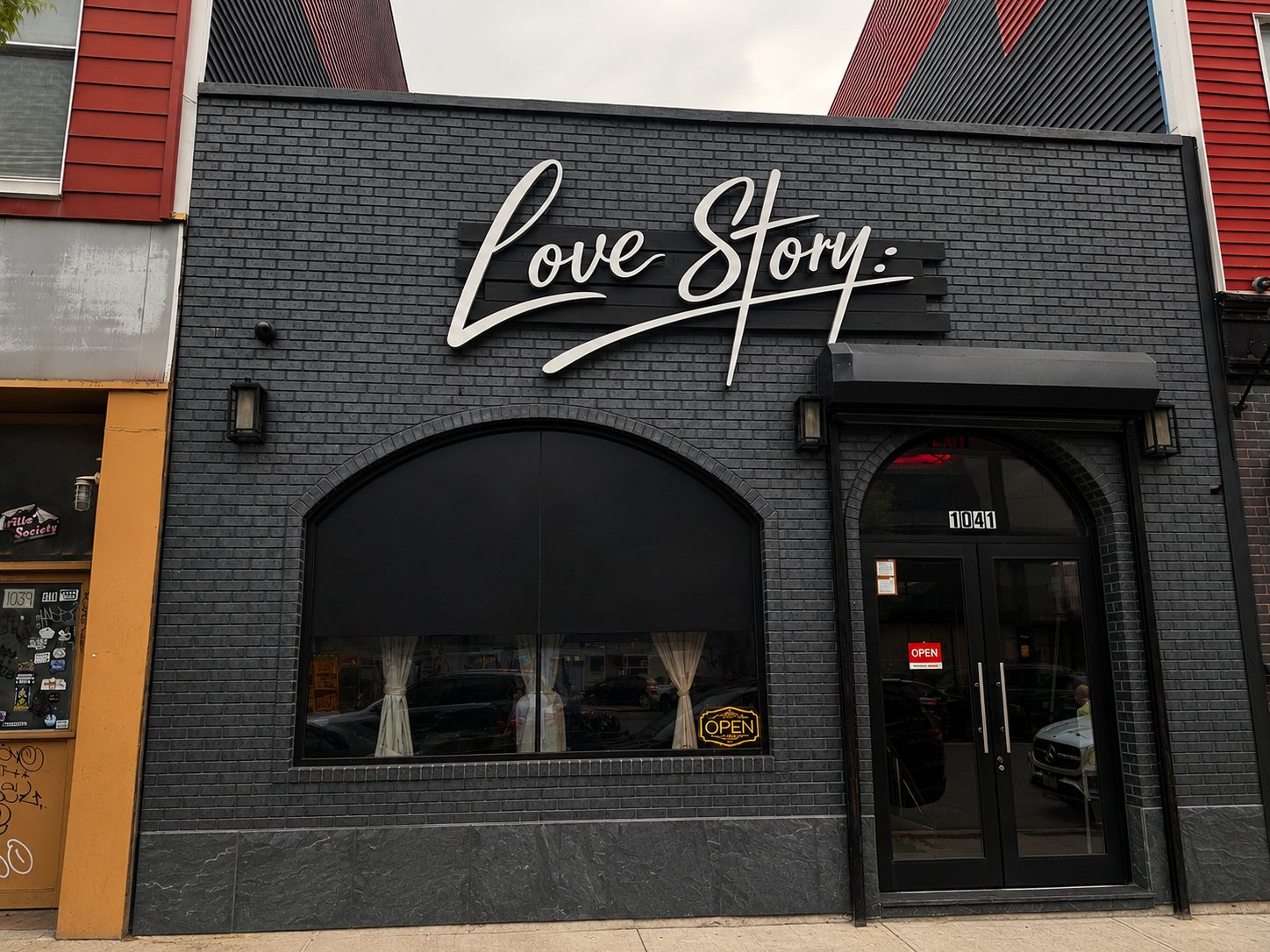 Love Story Brooklyn storefront — white script sign on dark brick at 1041 Flushing Avenue
